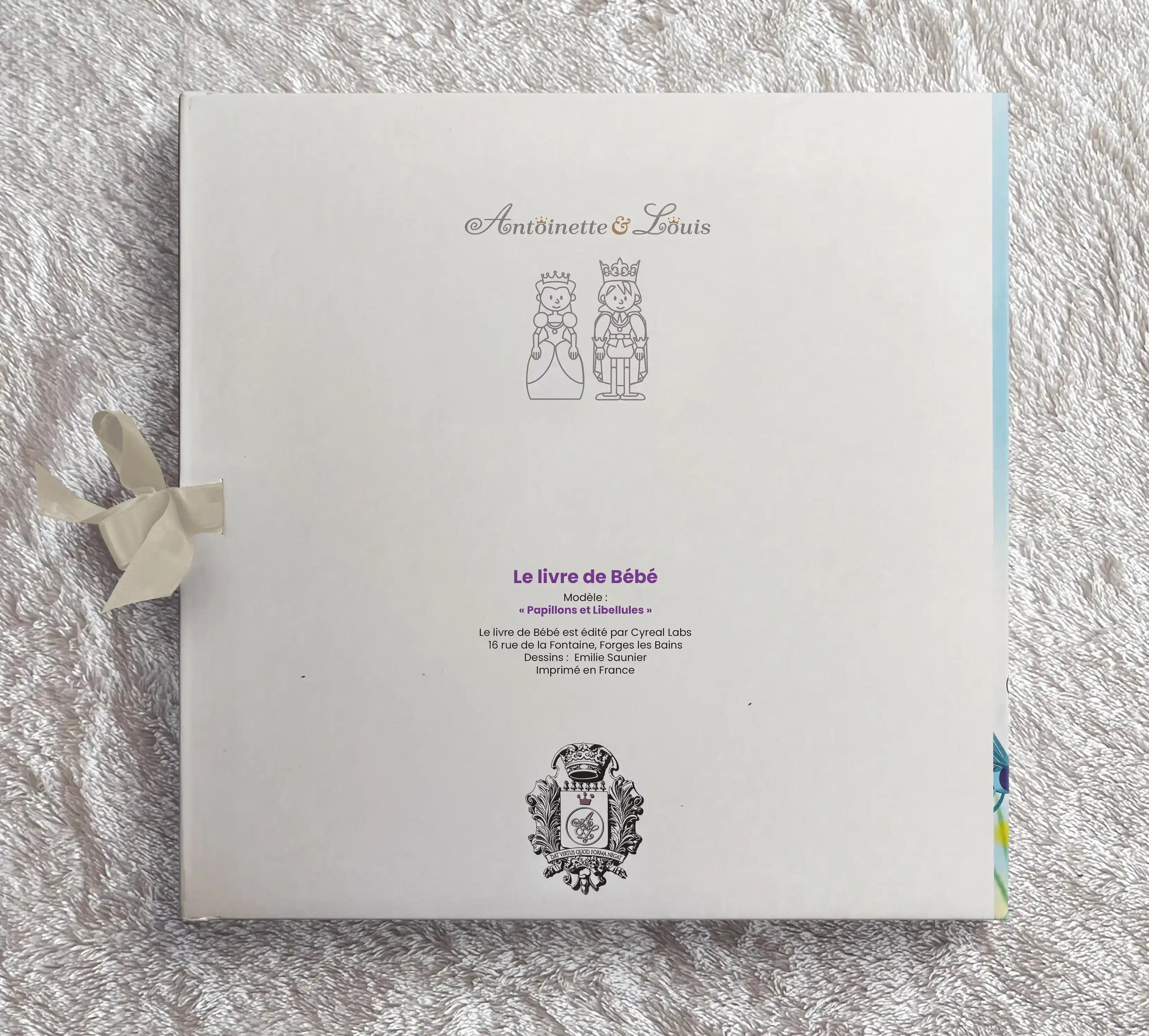 Dos de l’album photo naissance Antoinette & Louis, modèle papillons et libellules, avec ruban violet et logo de la marque imprimé en France
