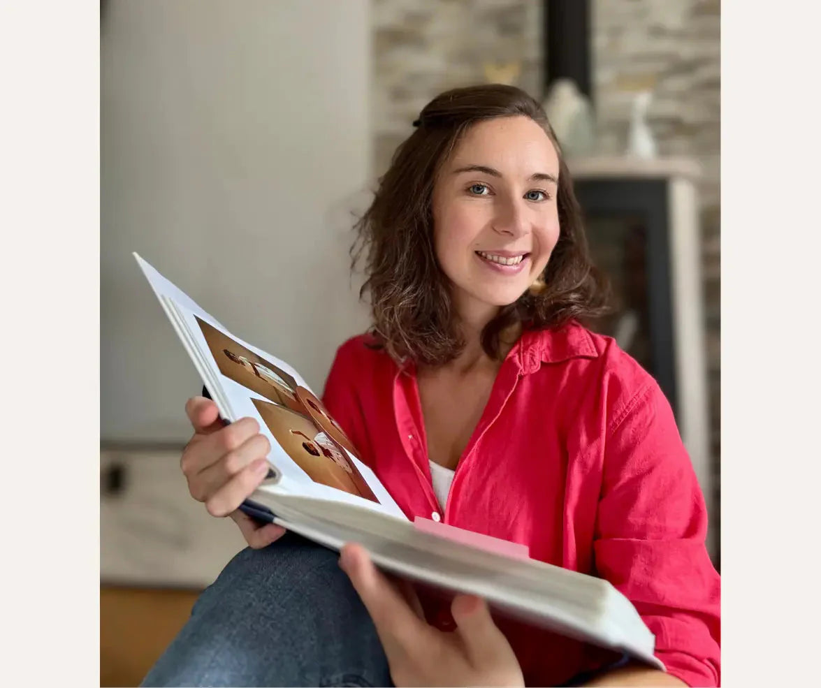 fondatrice d'Antoinette & Louis qui sourit avec un album photo entre ses mains