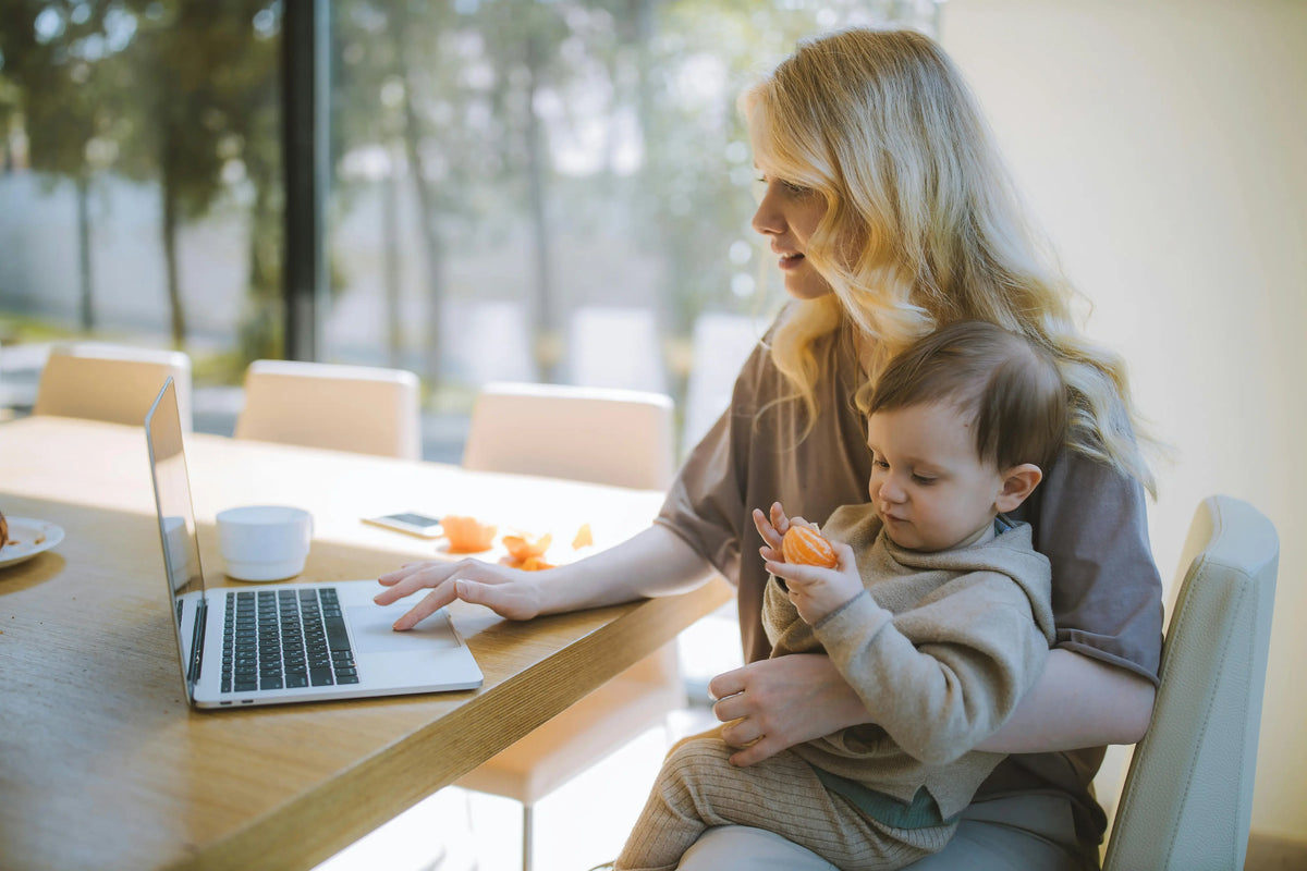 Maman solo qui travaille sur son ordinateur avec son fils sur ses genoux
